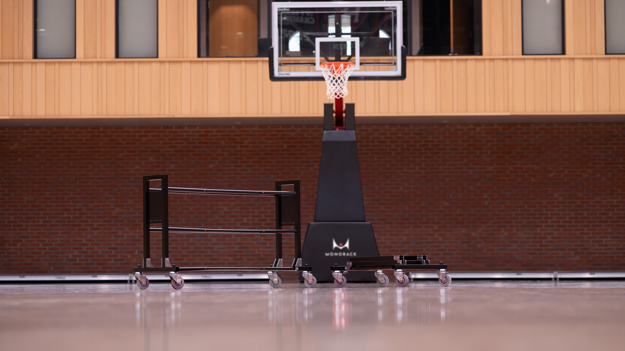 Two Monoracks pictured in front of a basketball hoop. One ball rack is collapsed, the other is fully assembled.