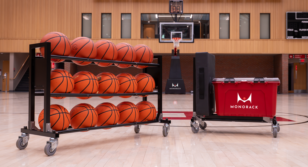 A Monorack ball rack loaded with 15 basketballs pictured in a basketball gym next to a second Monorack in cart-mode with equipment on it.
