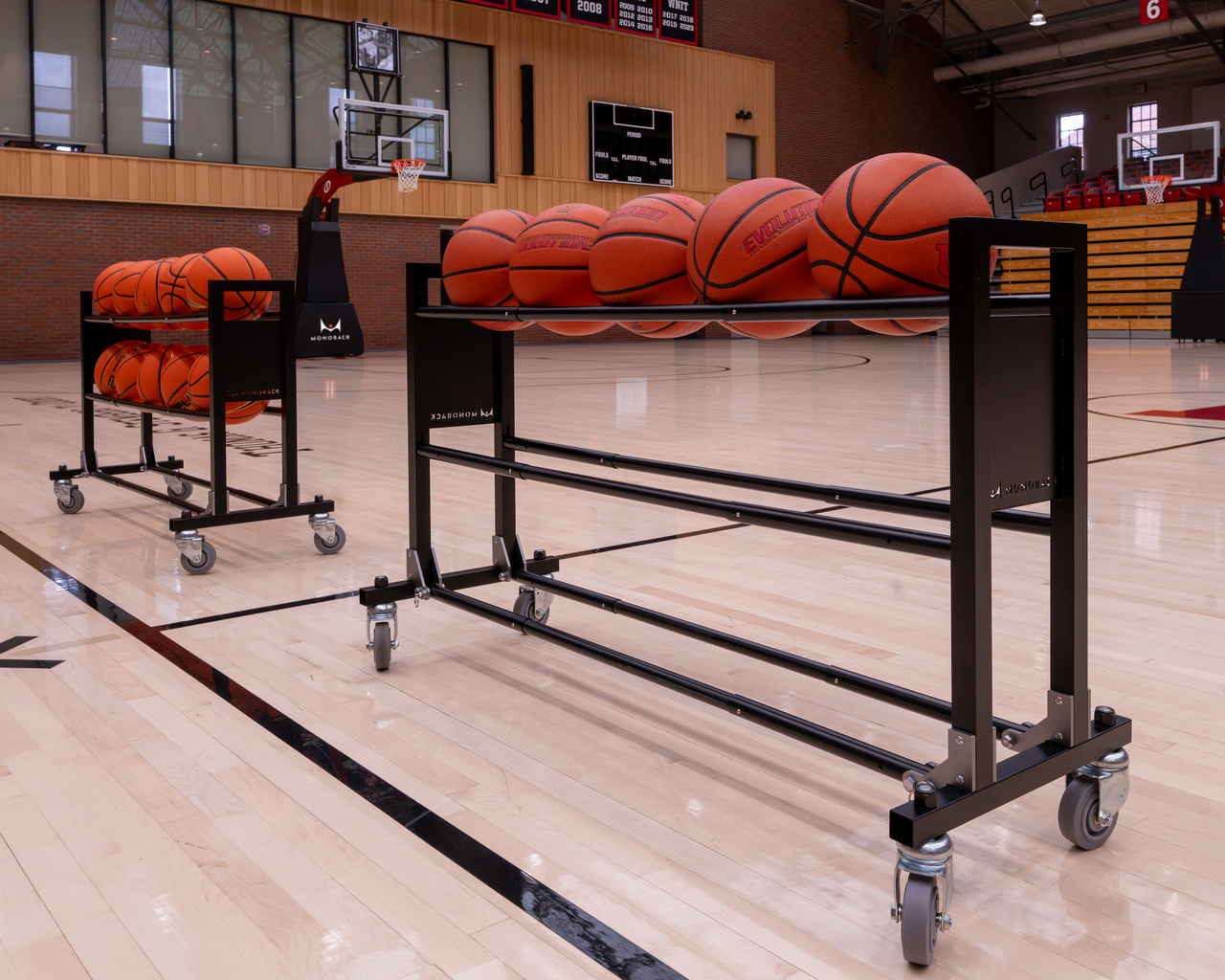 Two Monoracks on opposite halves of a basketball court, each loaded with basketballs.