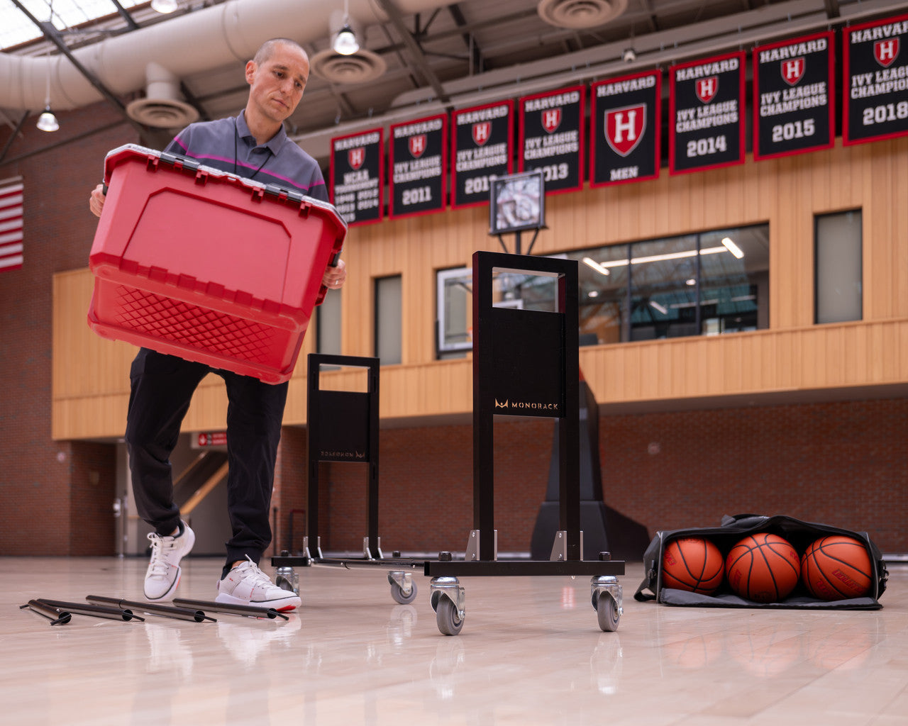 A coach carries a bin over to place on top of the Monorack.